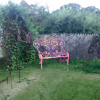 Яркая расписная скамейка в частном саду