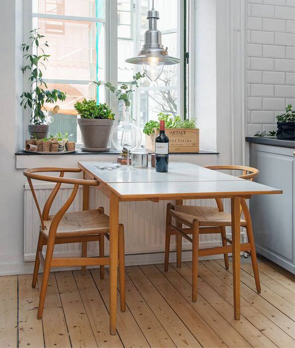 Кухонный столик с откидной поверхностью перед окном кухни частного дома