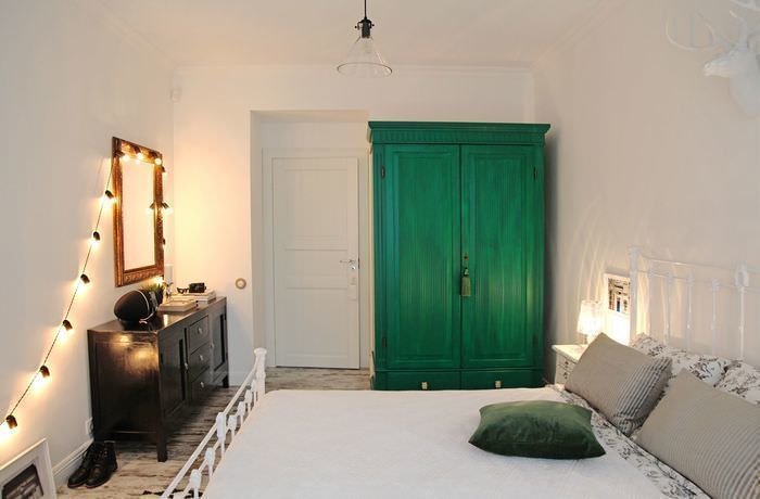 Интерьер светлой спальни с зеленым шкафом